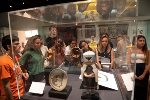 students looking at a case of native american art consisting of small wooden carved sculptures and ceramic pots