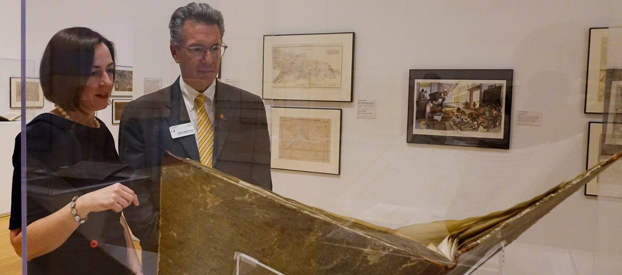 2 people in a gallery looking at an archival book