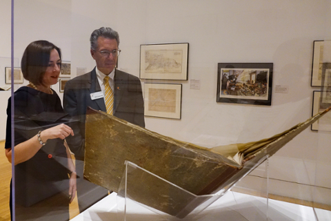 2 people in an art gallery looking at an archival book