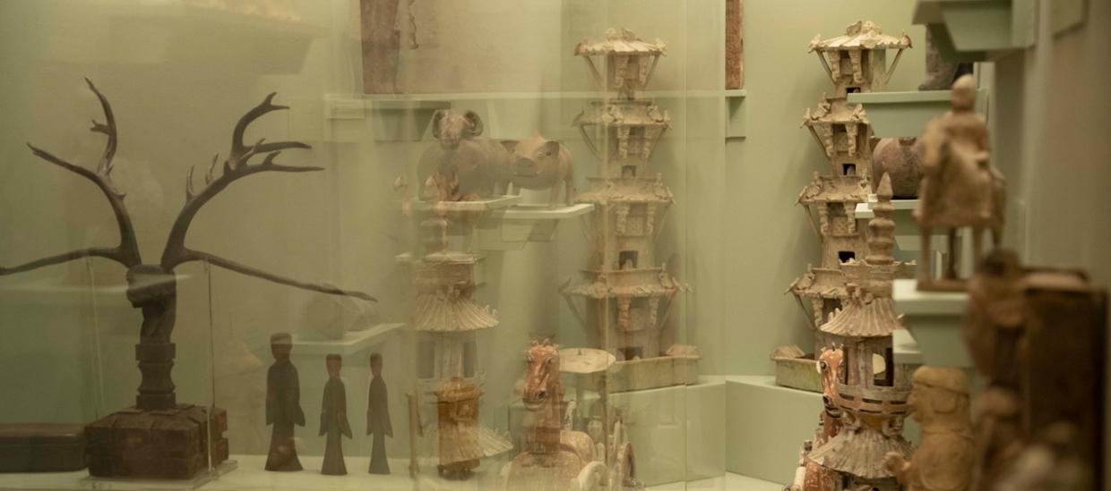 image of ceramics from china in a glass case. Som wood sculptures as well