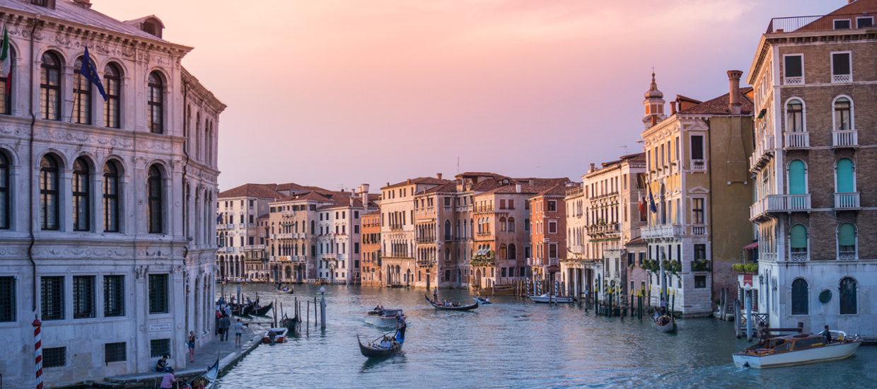 view of a large canal in Venice italy. sunrise or sunset with Gondola's in the water and buildings on each side of the canal