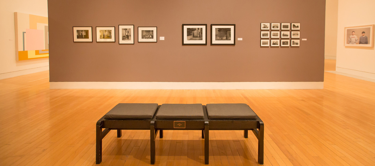 image of art gallery with photographs on wall and bench in center