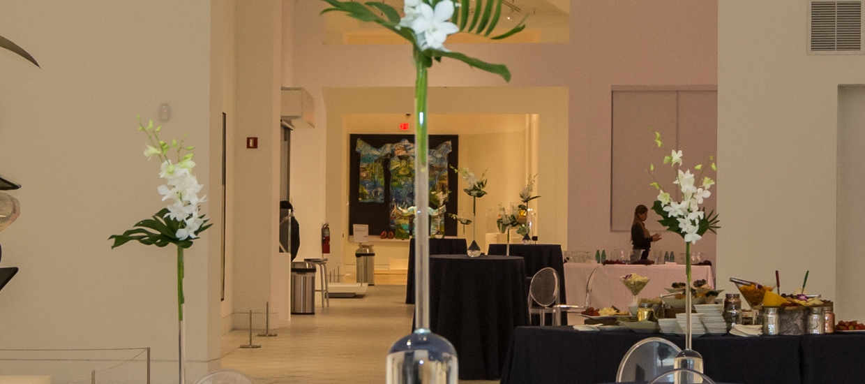 picture of tobin gallery set up for a facility rental with talbes with blue tablecloths with white flowers on the tables