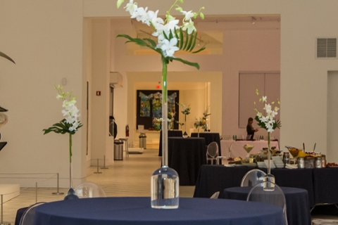 picture of tobin gallery set up for a facility rental with talbes with blue tablecloths with white flowers on the tables