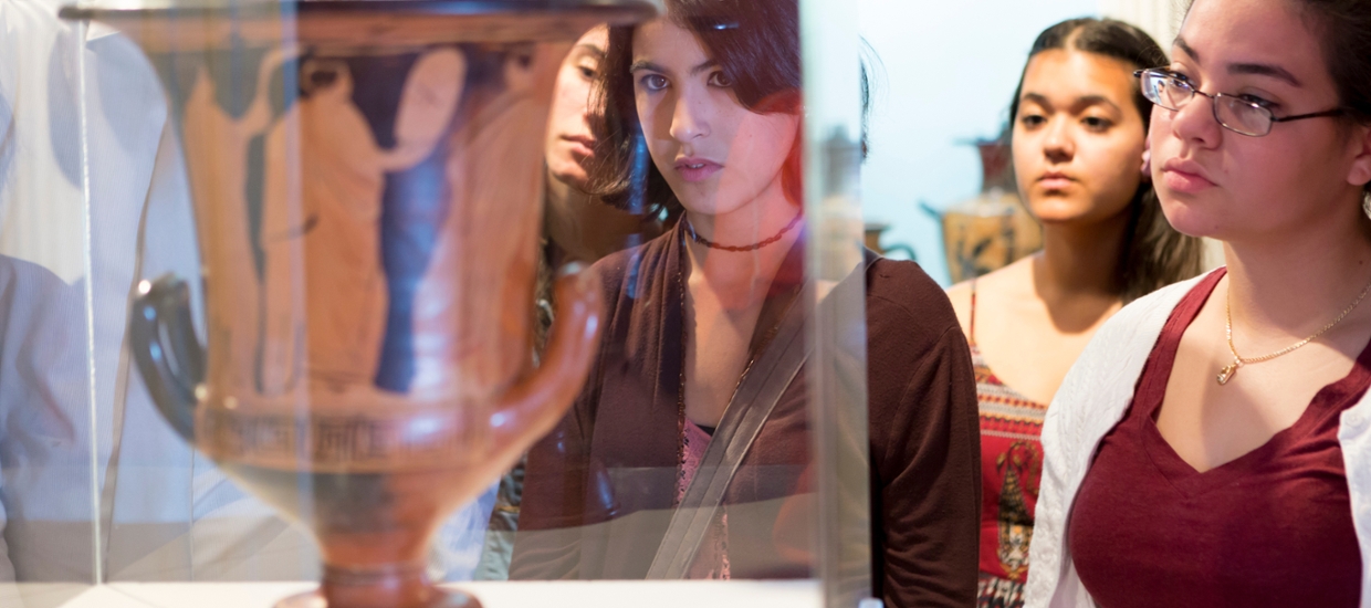 woman looking at an ancient Greek vase that is red and black 