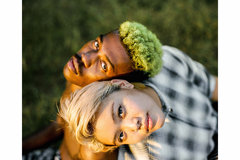 color photograph of a white woman and black man shot from above their heads. Each figure is looking up at the camera.